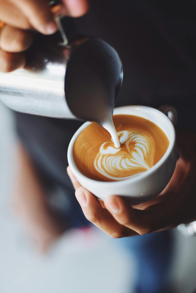 pexels-photo-302896-302896 Close-up of barista pouring milk to create stunning latte art in a coffee shop setting.